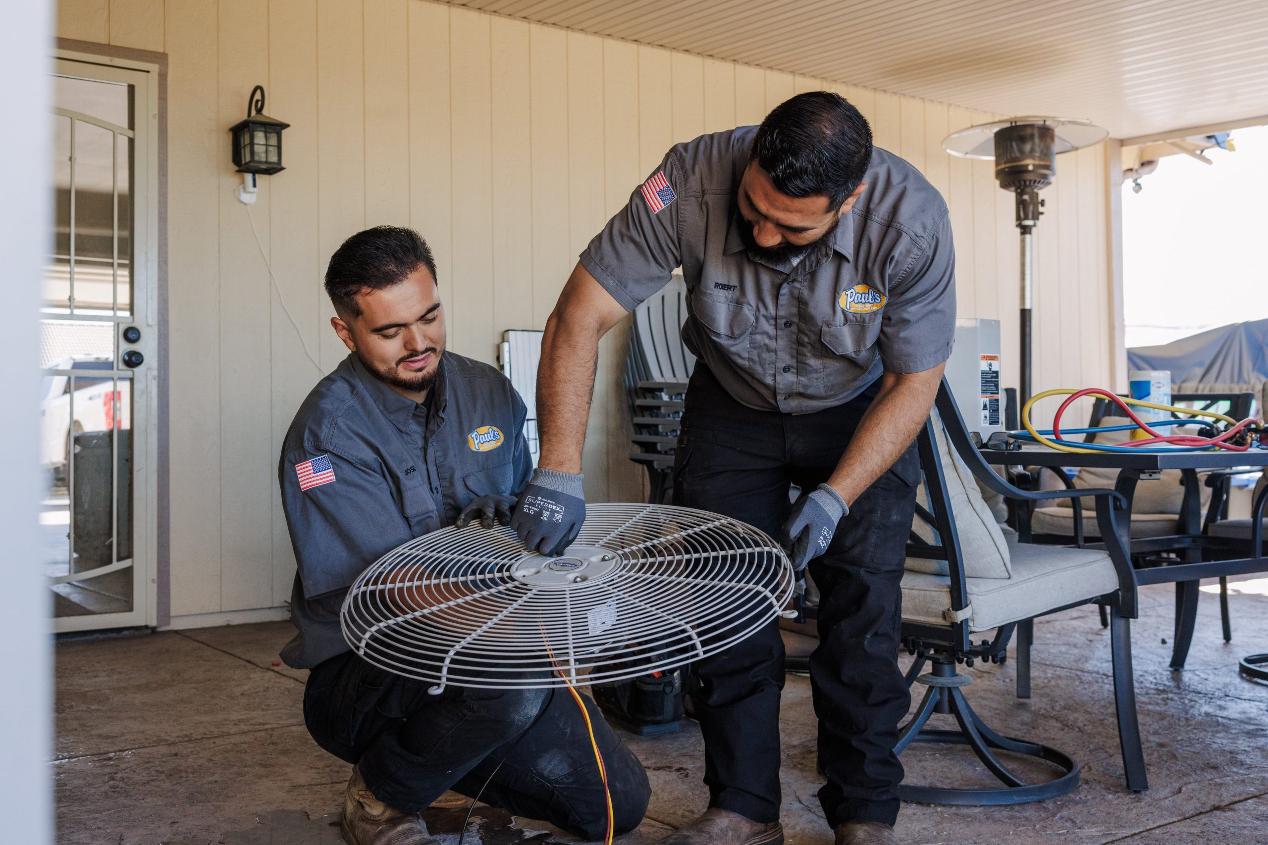 Two HVAC technicians servicing an outdoor air-conditioning unit