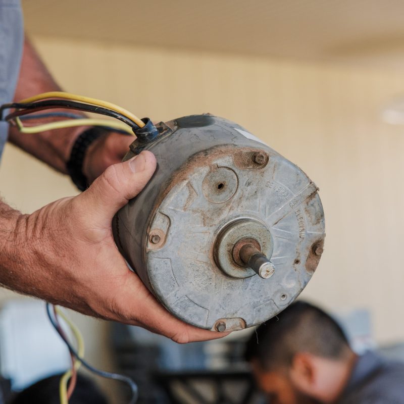 Technician holding a wired electric motor during repair