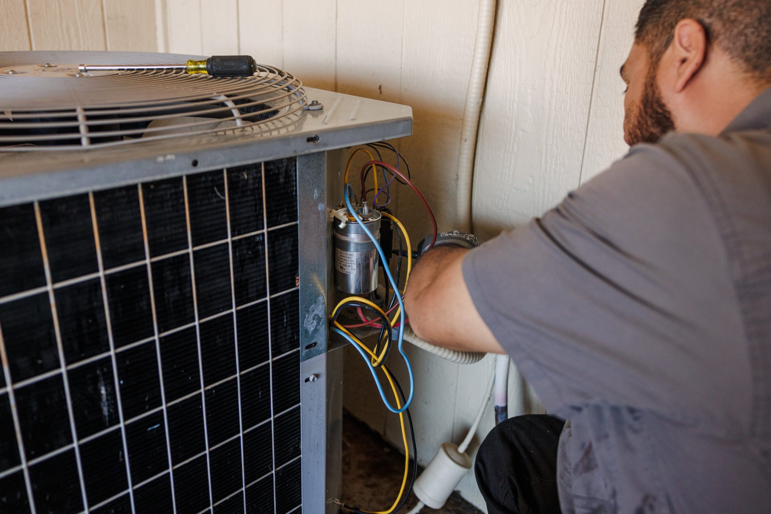 Technician servicing an air conditioner condenser unit