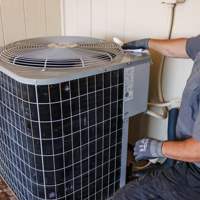 HVAC technician servicing an outdoor air conditioning condenser unit