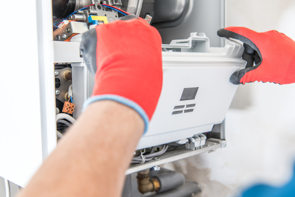 Technician removing boiler control panel wearing red safety gloves